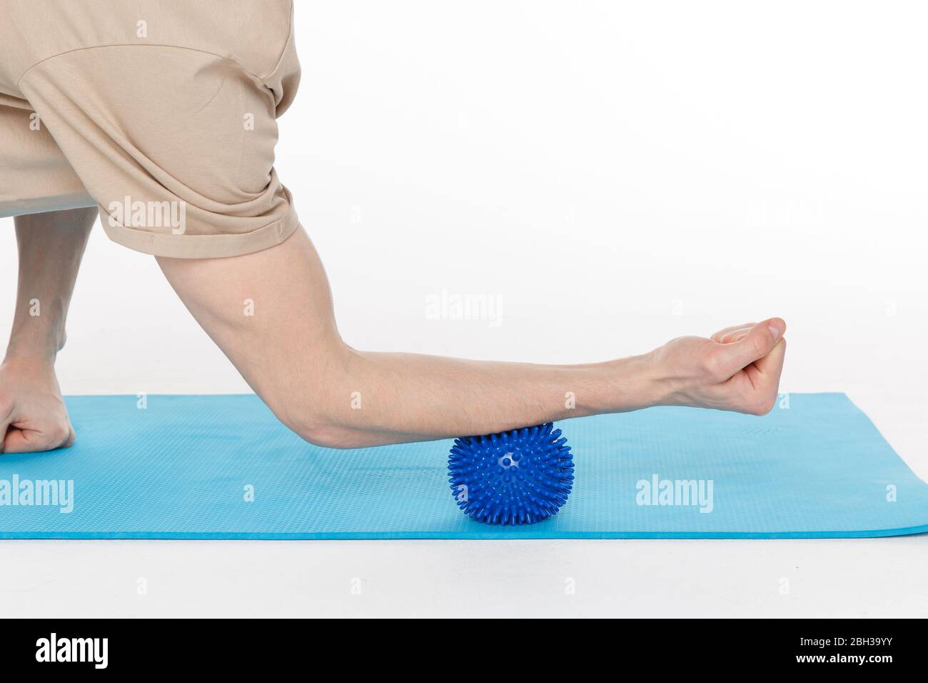 Handsome man shows exercises using the ball with spikes for a