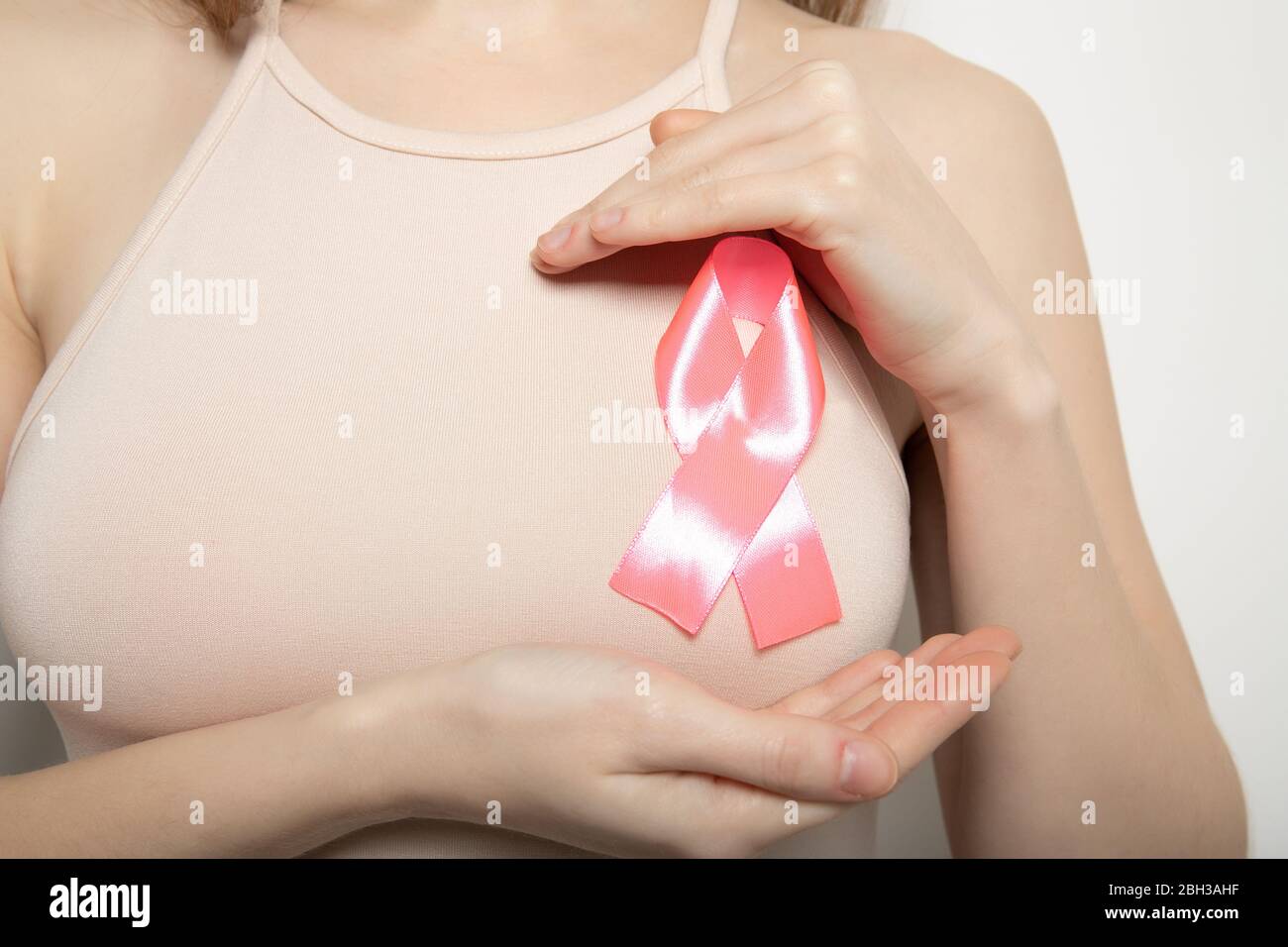 The symbol of the fight against breast cancer. Pink ribbon on the girl’s chest. Stock Photo