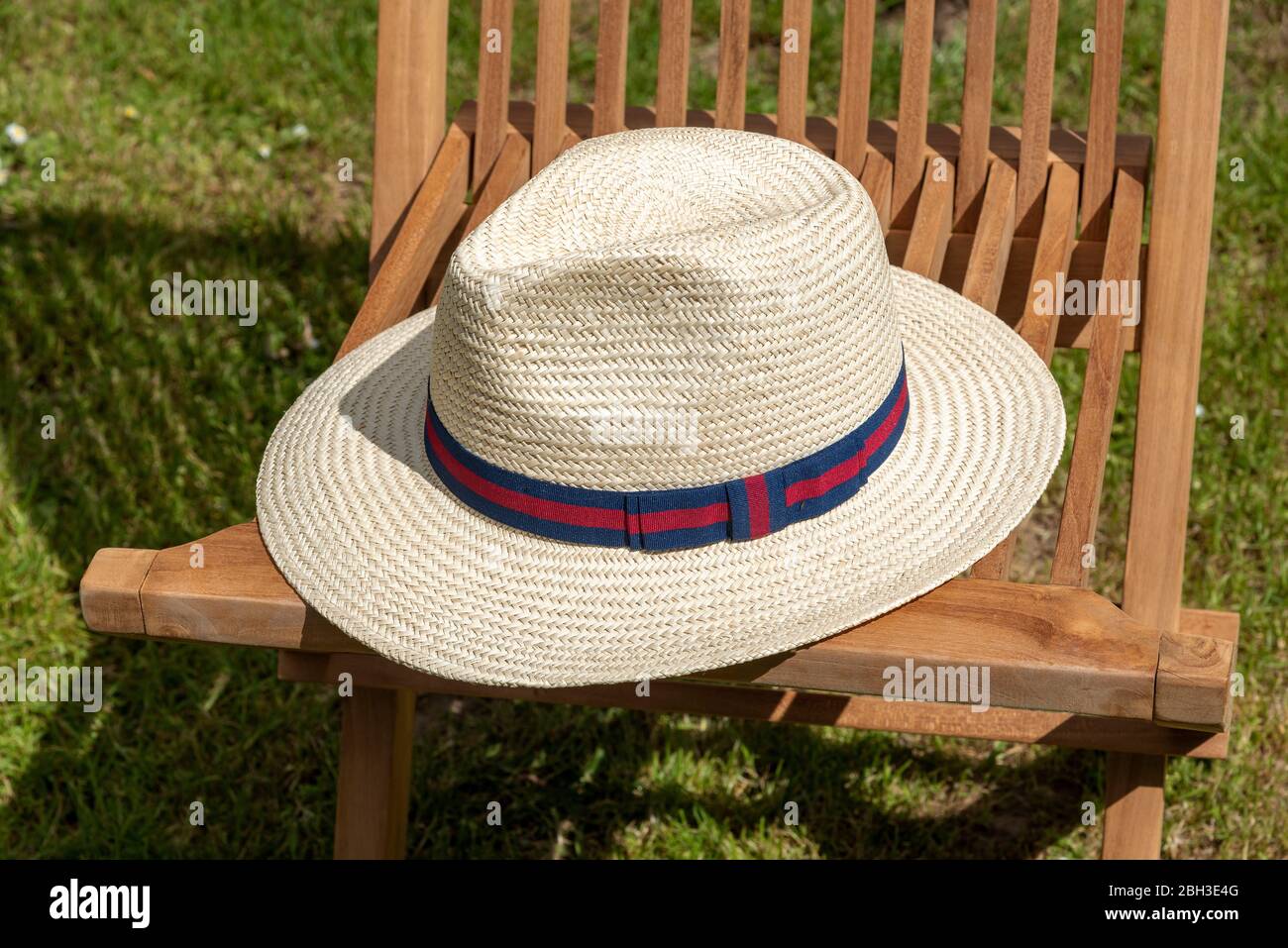 England, UK, 2020. A gentleman's straw hat placed on a wooden deck chair. Stock Photo