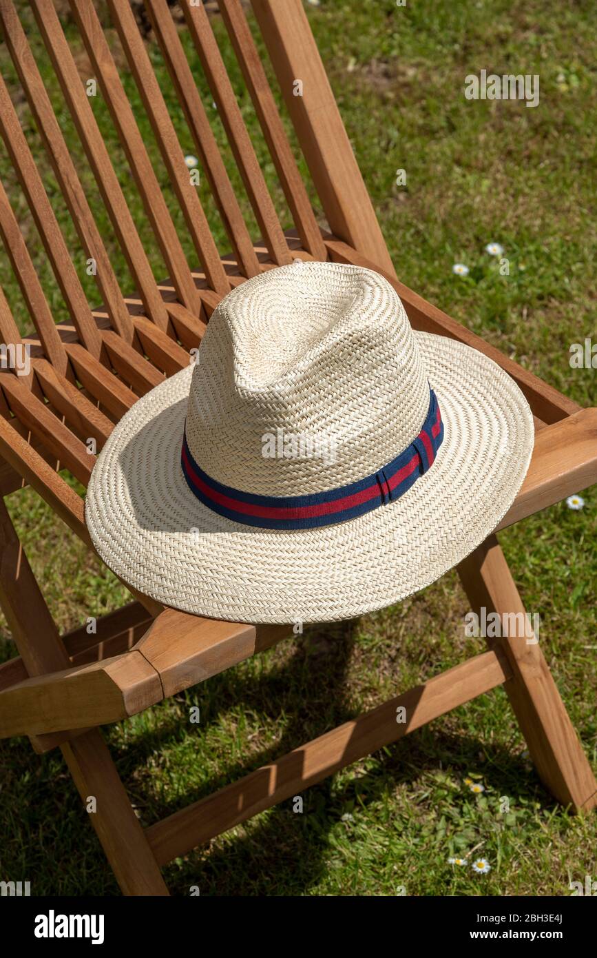 England, UK, 2020. A gentleman's straw hat placed on a wooden deck chair. Stock Photo