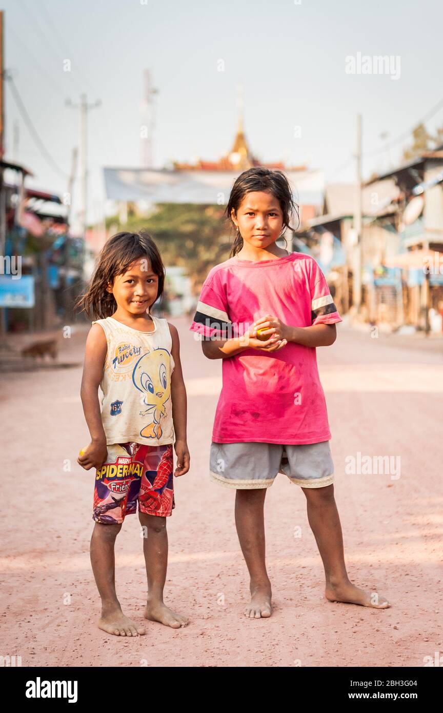 Two young Cambodian girls pause for a photo along the main road at the floating village of Kampong Phluk, near Tonle Sap Lake, Cambodia. Stock Photo