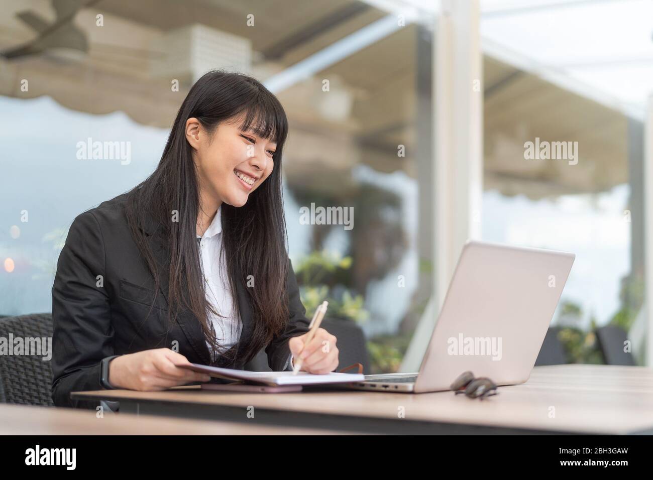 Business Asian woman working on computer in cafe outdoor - Young female entrepreneur using laptop in office Stock Photo
