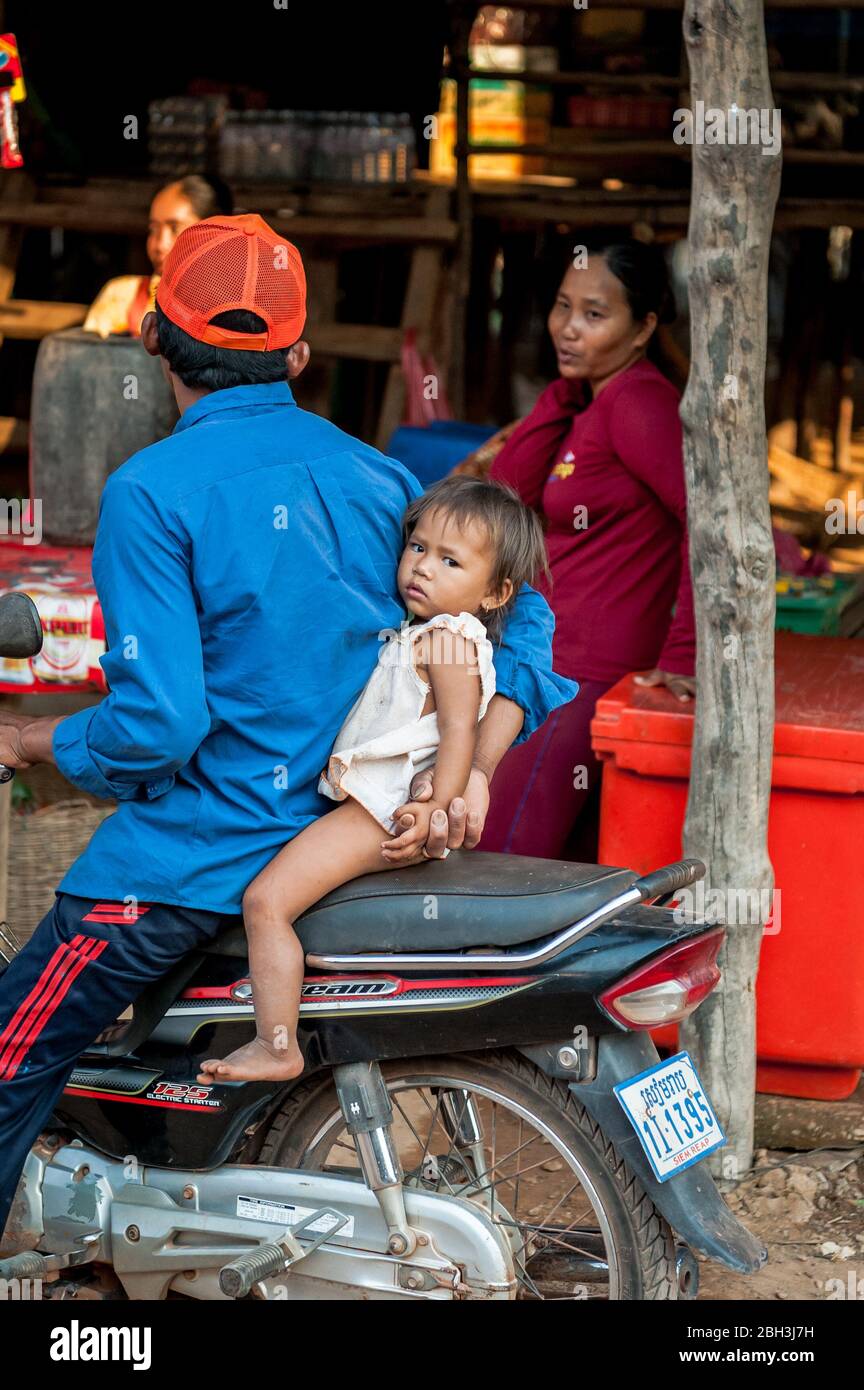 A baby is held on to a motorbike in the floating village of Kampong Phluk, Cambodia. Stock Photo