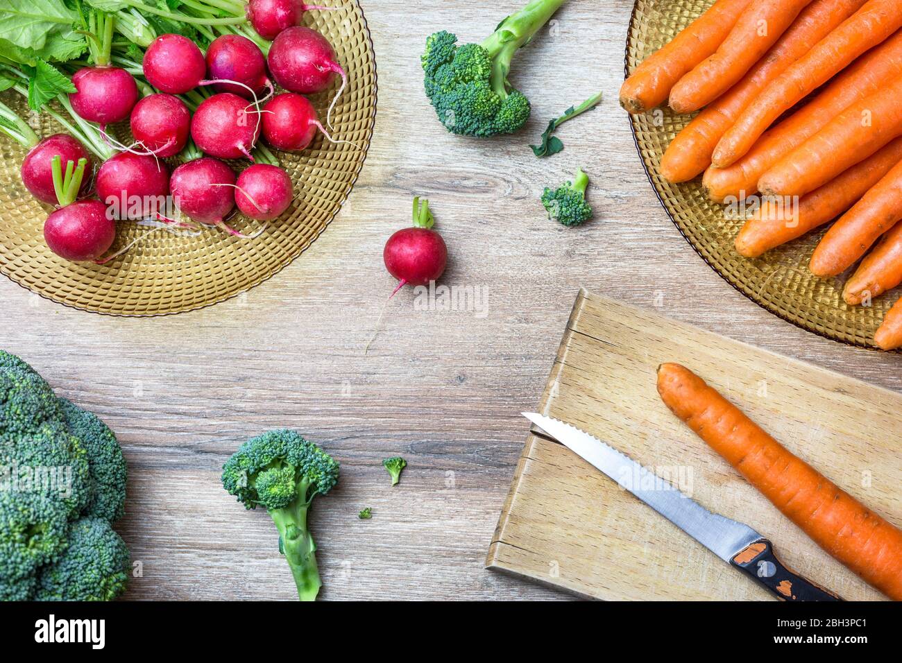 Fresh organic red radishes, carrots and broccoli on wooden background. Top view with copy space. Healthy nutrition concept. Stock Photo