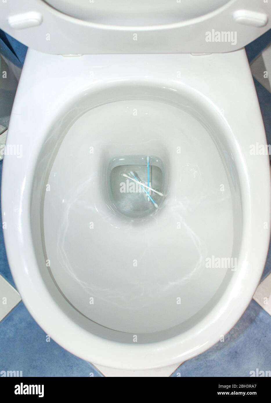 Cotton swabs thrown in a toilet of a home. Concept of bad habits for the environment, pollution