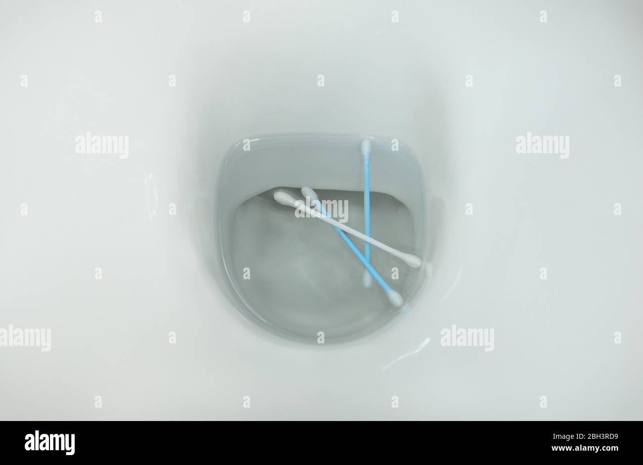 Cotton swabs thrown in a toilet. Concept of bad habits for the