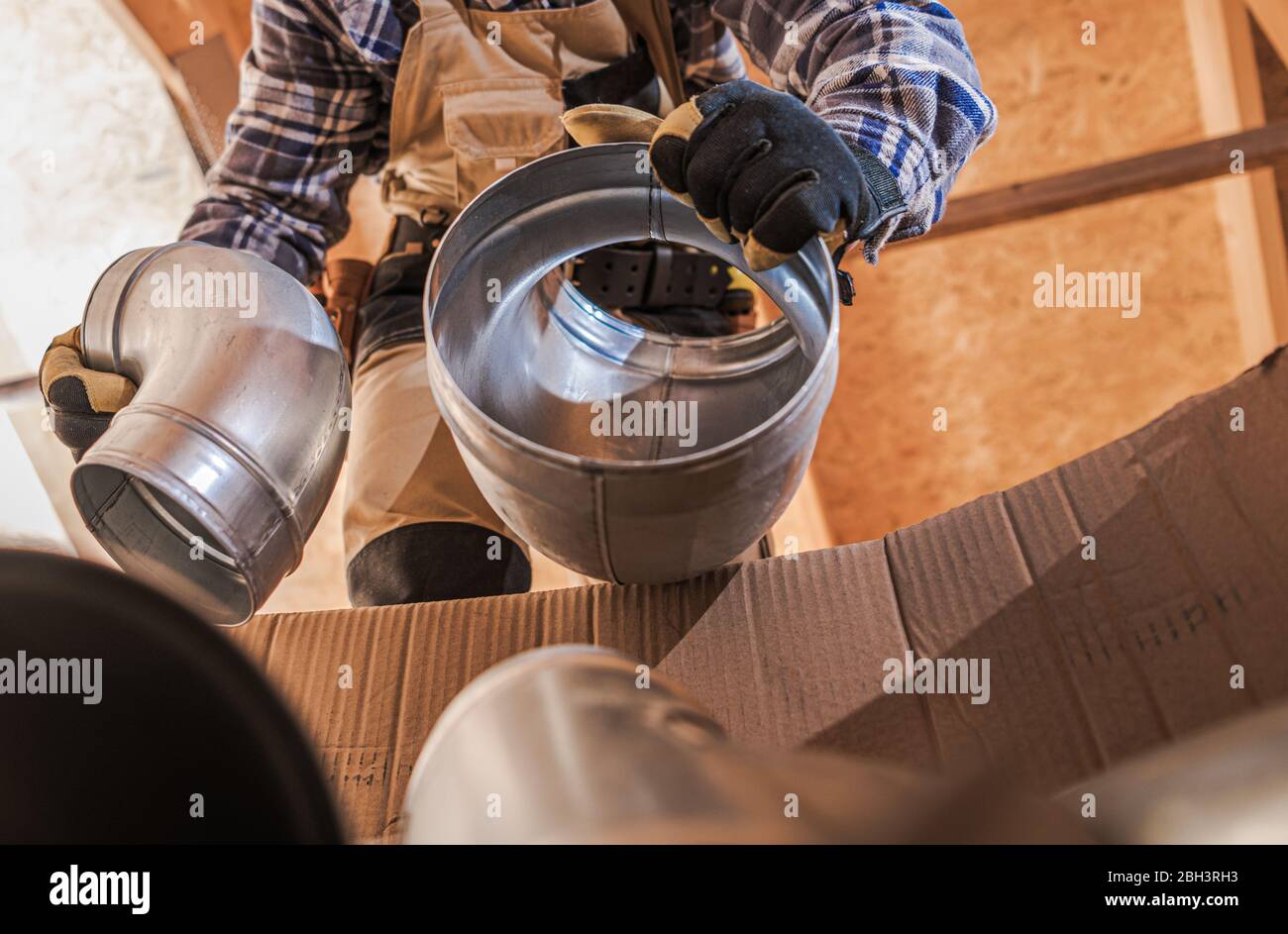 HVAC Worker Getting Ready To Assemble Vent Pipes in House Stock Photo