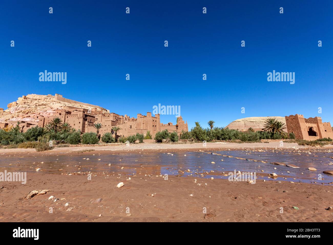 Stones as crossing point via Ounila River and the Historic ighrem or ksar (fortified village), Aït Benhaddou, Morocco Stock Photo