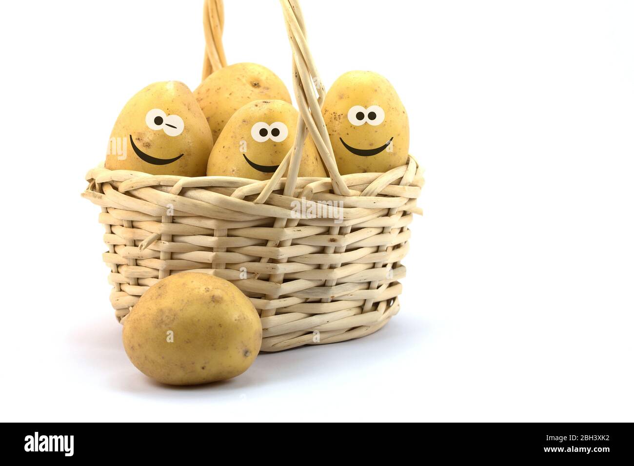 Potatoes in basket with funny face against white background Stock Photo