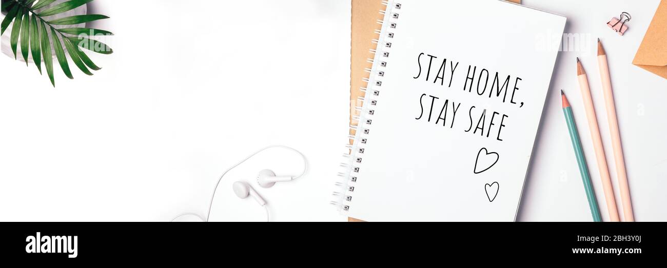 Words stay home, stay safe written in notebook, concept of self quarantine at home as preventative virus Flat lay Banner Stock Photo