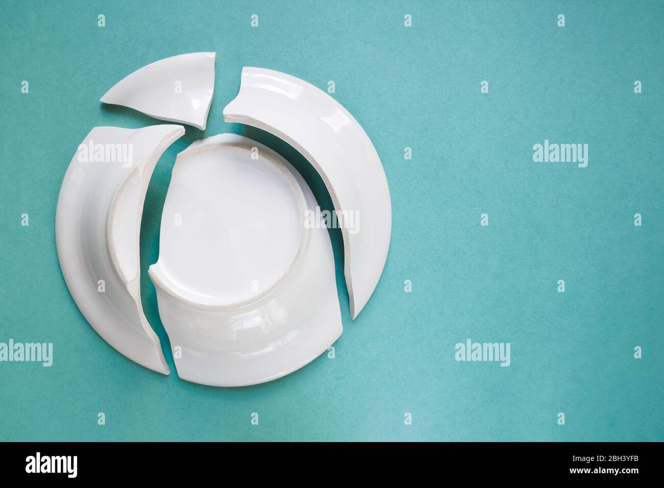 broken white plate on a green background, copy space, top view Stock Photo