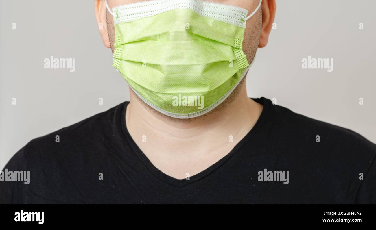 Young man with a surgical mask on his face protecting himself from the ...