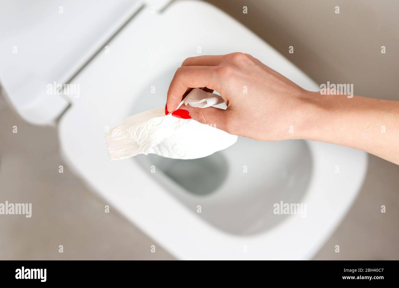 Woman throwing a dry and dirty napkin in the toilet bowl. Cleaning the