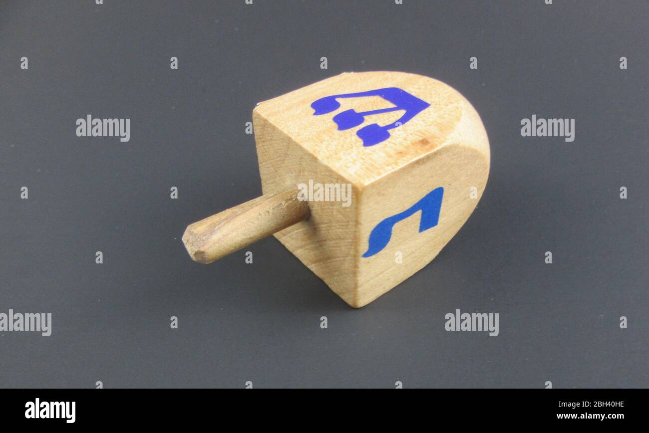 A wooden dreidel with the Hebrew letters shin and nun visible, which is used in game for children during the festival of Hanukkah Stock Photo