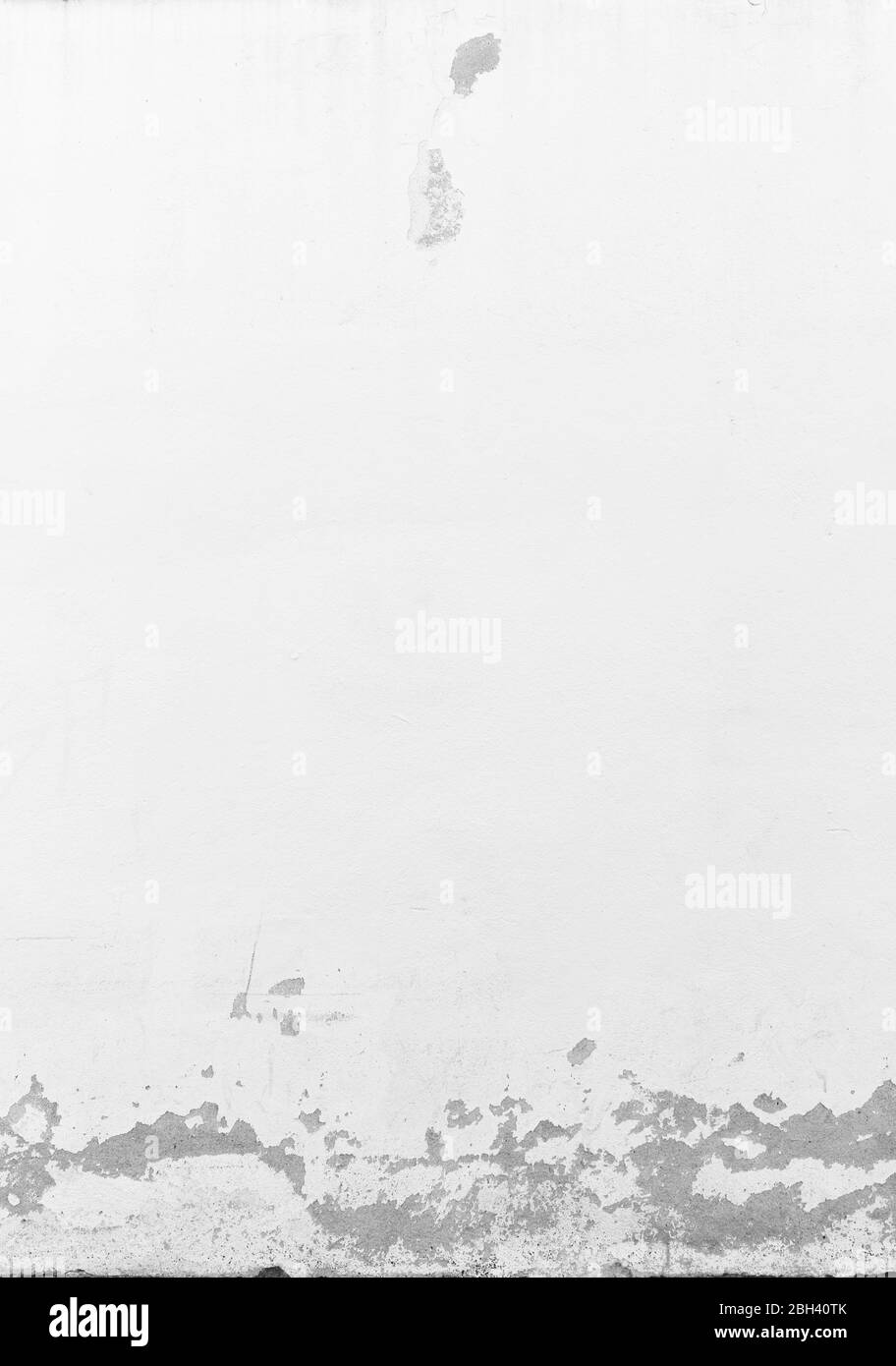 Close-up of a weathered and old concrete wall, white paint has partly peeled off. Abstract full frame textured background in black & white. Copy space Stock Photo