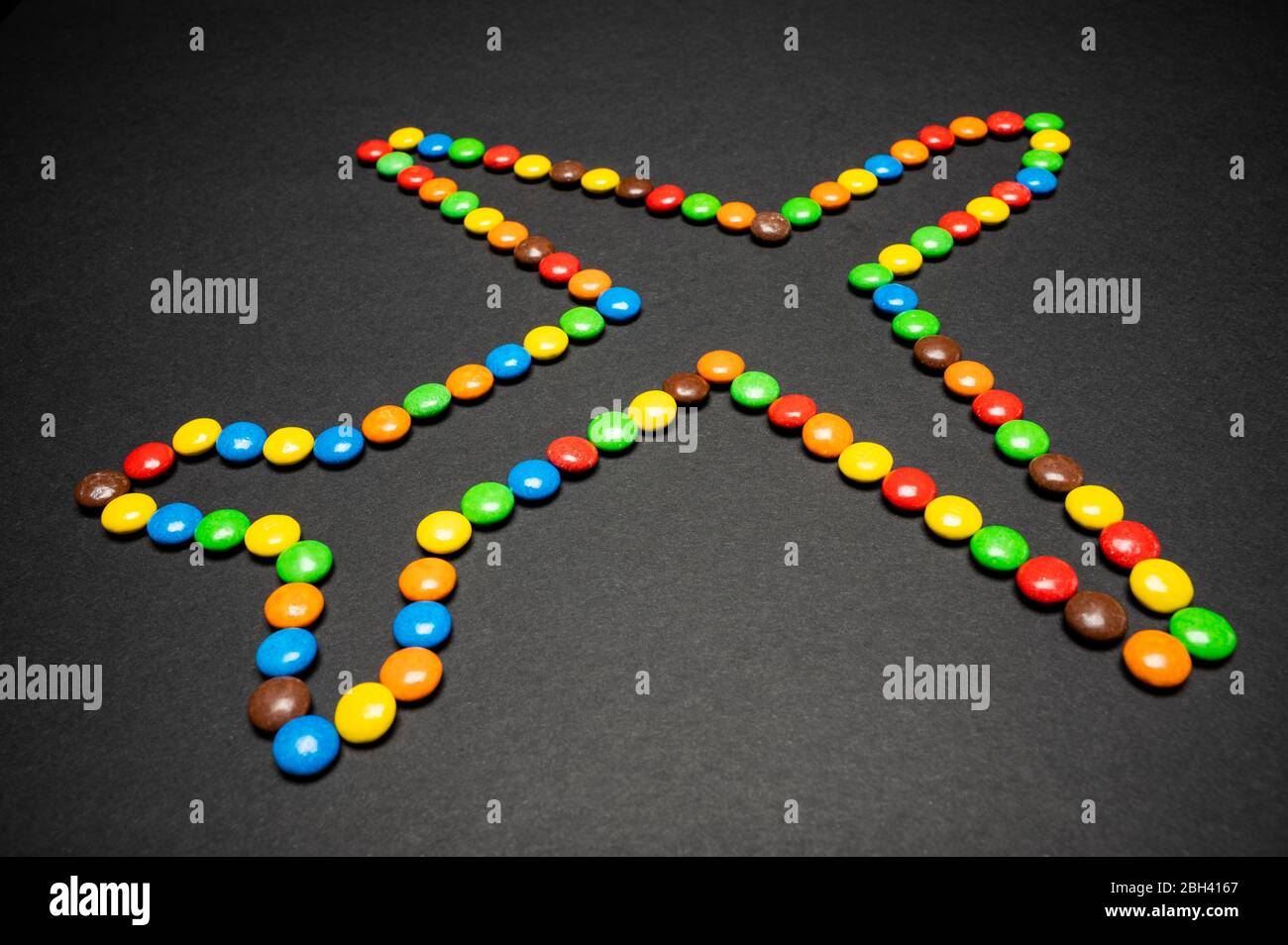 M&M candy pieces making an airplane shape on a black background Stock Photo