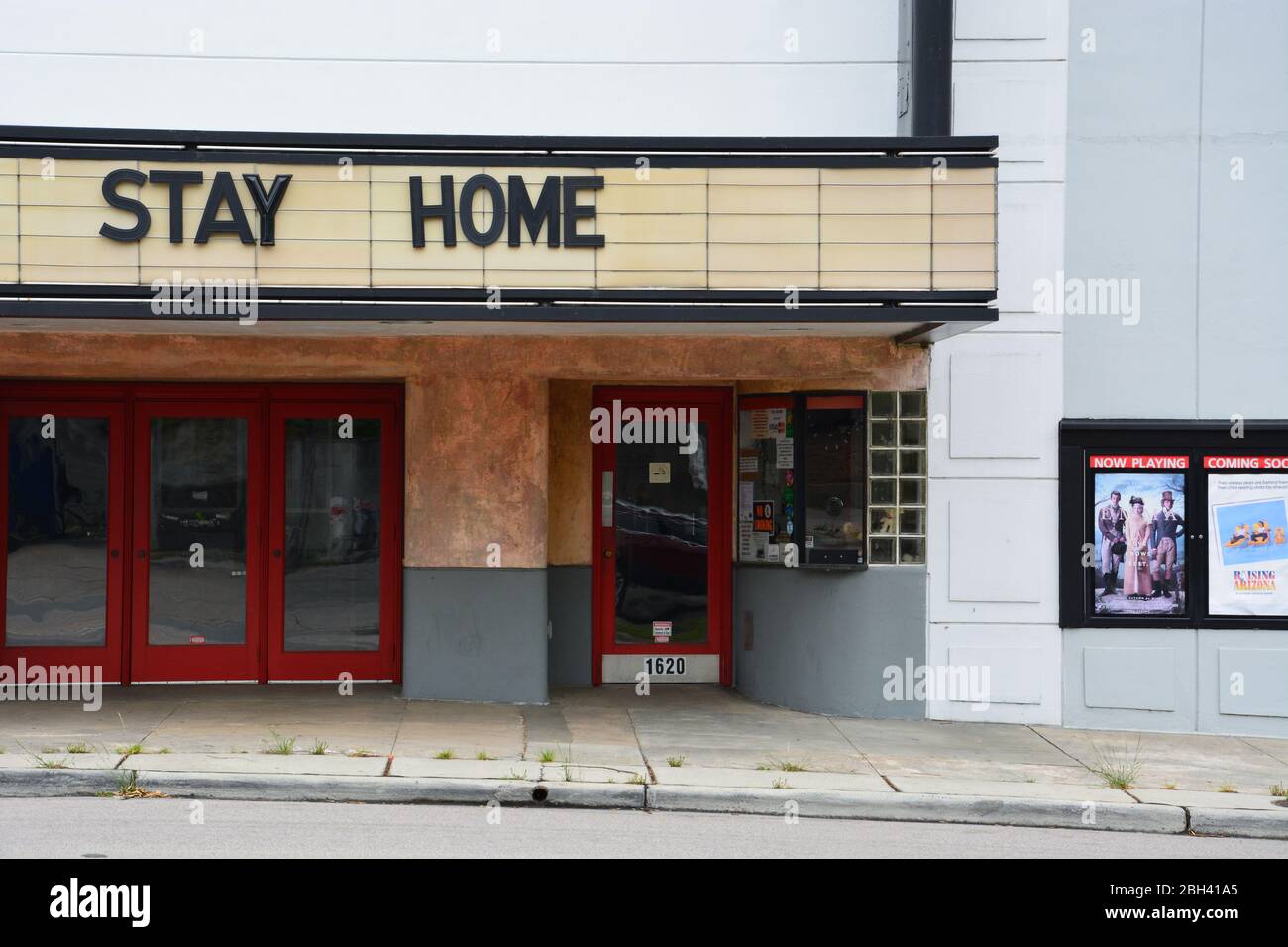 A sign reading Stay Home is posted on a small movie theater closed during the Coronavirus Covid 19 pandemic. Stock Photo