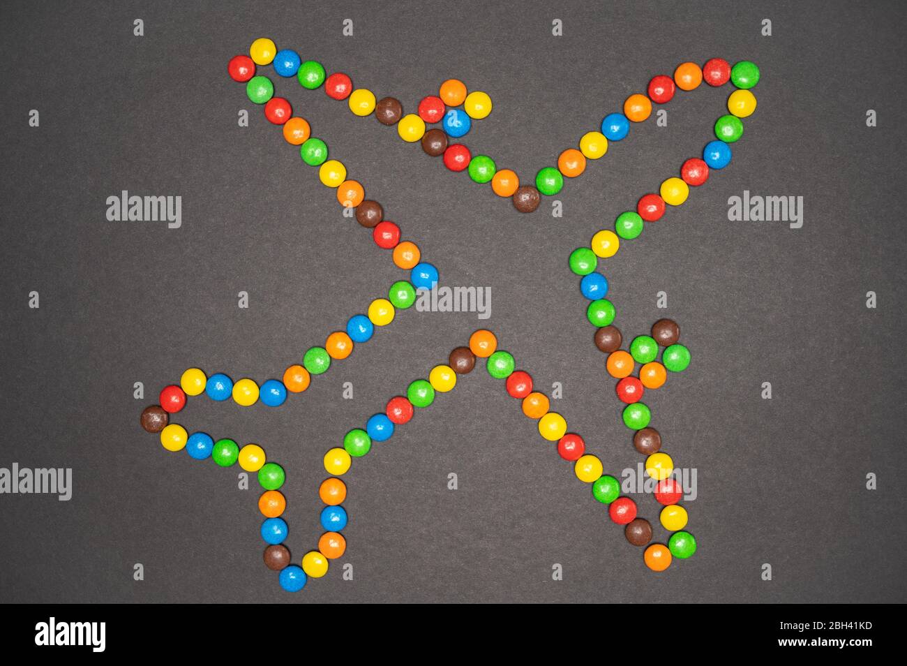 M&M candy pieces making an airplane shape on a black background Stock Photo