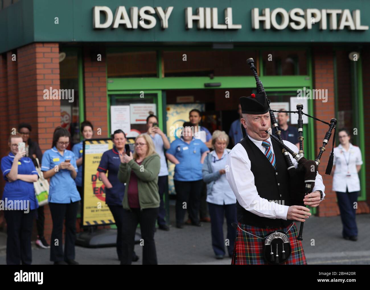 A piper from the Bessbrook Crimson Arrow Pipe Band plays for staff outside Daisy Hill Hospital in Newry, Northern Ireland, to salute local heroes during Thursday's nationwide Clap for Carers initiative to recognise and support NHS workers and carers fighting the coronavirus pandemic. Stock Photo