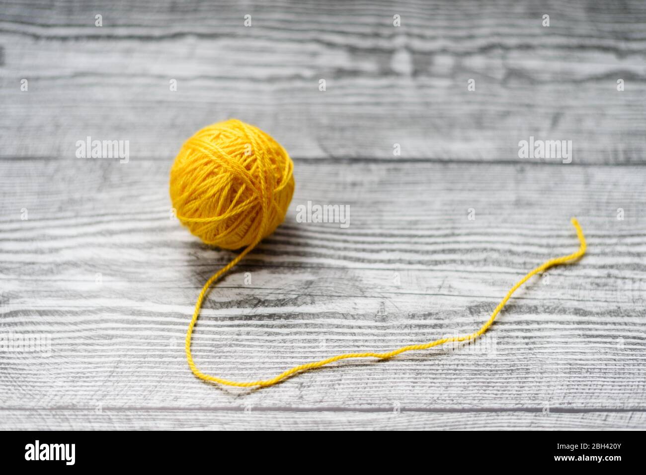 One ball of yellow wool knitting needles on the wooden grey background. Stock Photo