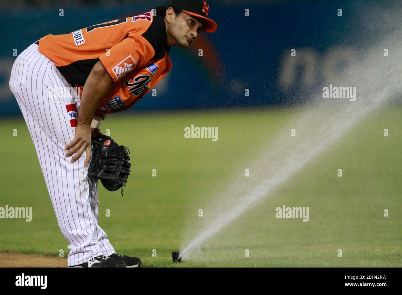 water sprinklers are activated during the game se activan los aspersores de agua durante el juego   .Jesse Gutierrez observa uno de los aspersores que Stock Photo
