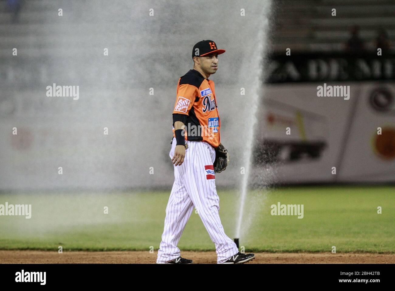 water sprinklers are activated during the game se activan los aspersores de agua durante el juego .  Carlos Gastelum junto a uno de los aspersores que Stock Photo