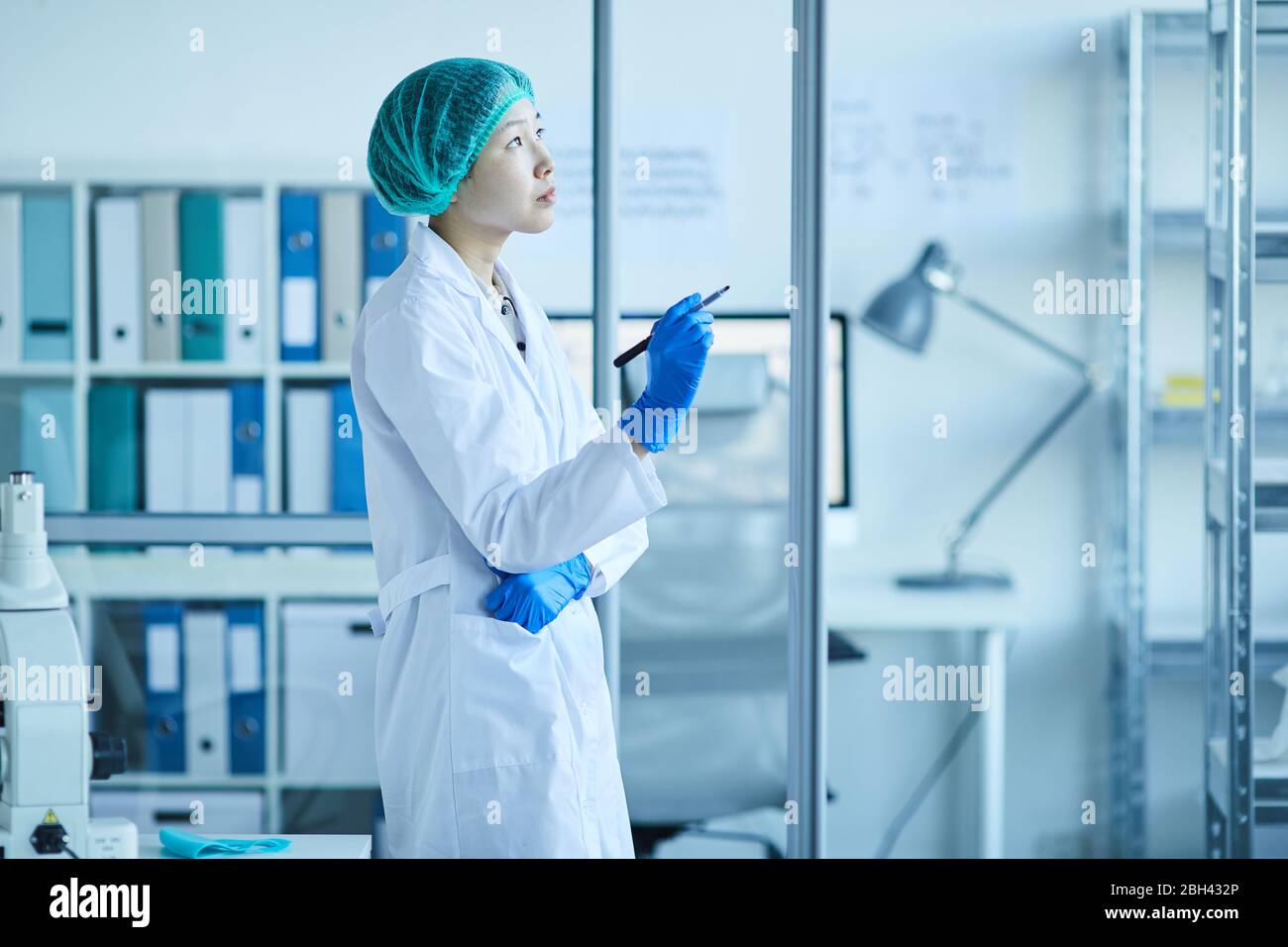 Pensive female doctor in white coat standing at the office and thinking about something Stock Photo