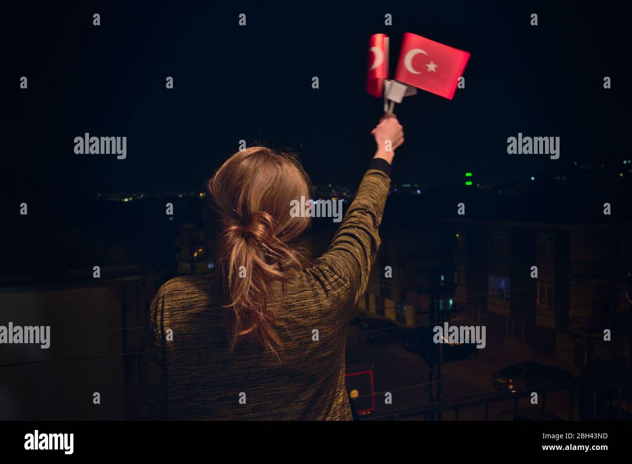 Turkish Woman Holding, Turkish Flags at night Celebrating April 23 National Sovereignty Children's Day Stock Photo