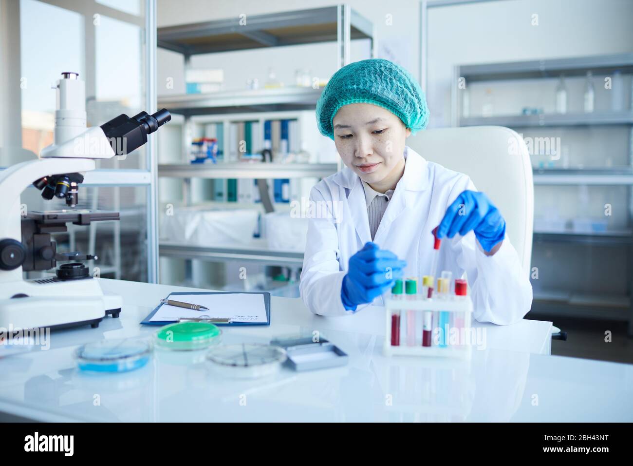Asian nurse sitting at the table and examining the results of blood samples in the lab Stock Photo