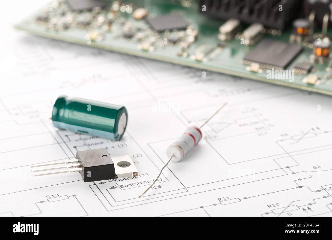 Transistor, resistor and capacitor electronic parts or components in front of pcb board with pcb wiring diagram - electronic device repair concept, se Stock Photo