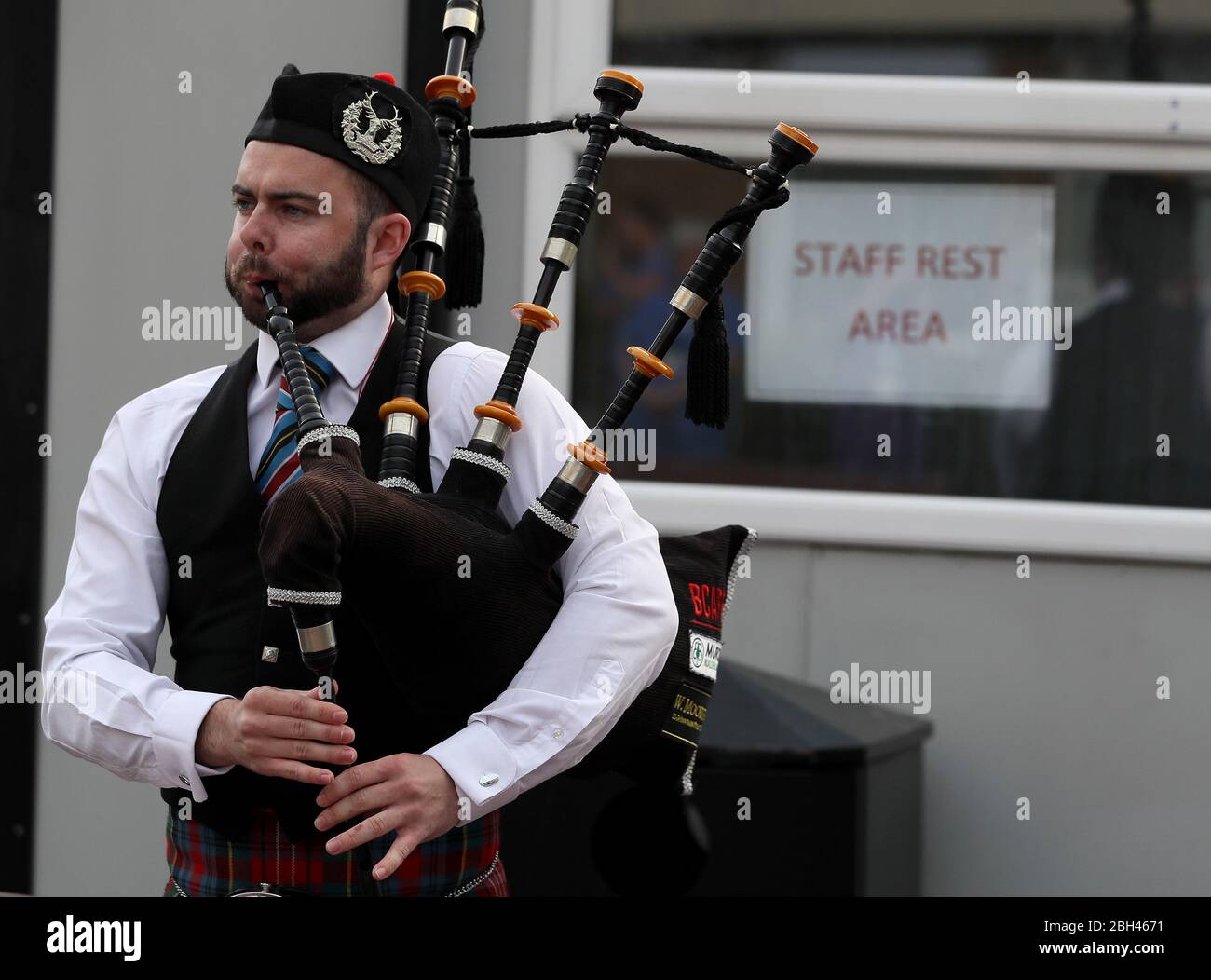 A piper from the Bessbrook Crimson Arrow Pipe Band plays for staff outside Daisy Hill Hospital in Newry, Northern Ireland, to salute local heroes during Thursday's nationwide Clap for Carers initiative to recognise and support NHS workers and carers fighting the coronavirus pandemic. Stock Photo
