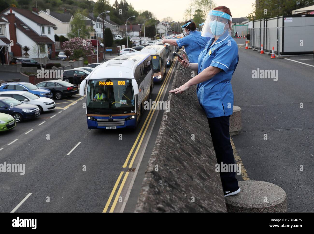 Healthcare workers watch as a convoy of buses beeping their horns passes Daisy Hill Hospital in Newry, Northern Ireland, to salute local heroes during Thursday's nationwide Clap for Carers initiative to recognise and support NHS workers and carers fighting the coronavirus pandemic. Stock Photo