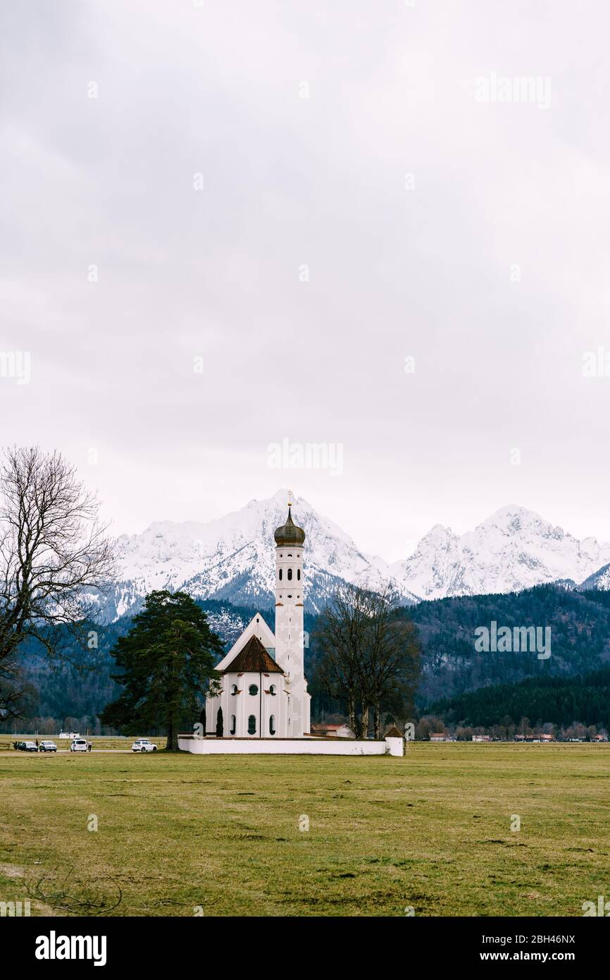 Church St. Coloman in Germany, in Bavaria, near Neuschwanstein Castle, overlooking the snow-capped mountains in March Stock Photo