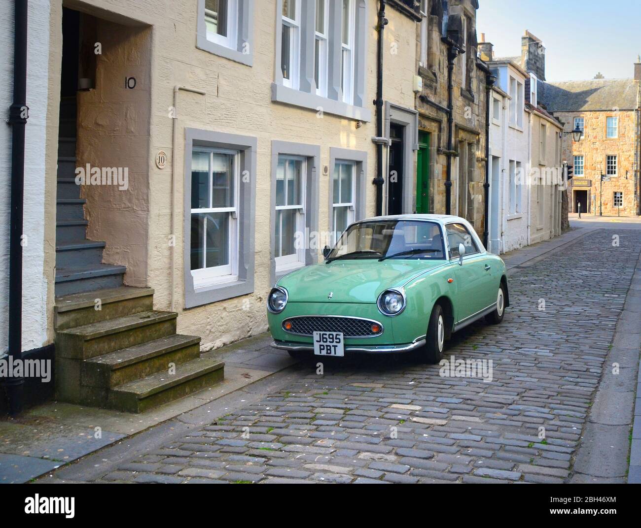 the retro 1960's looking car, the  Nissan Figaro parked on a cobbled street in the old town of St andrews, fife, Scotland Stock Photo