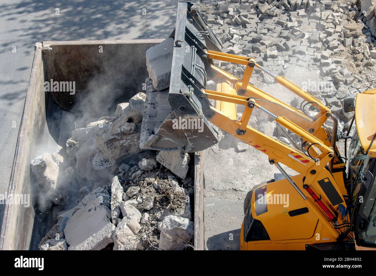 Bulldozer loader uploading concrete debris into dump truck at construction site Stock Photo