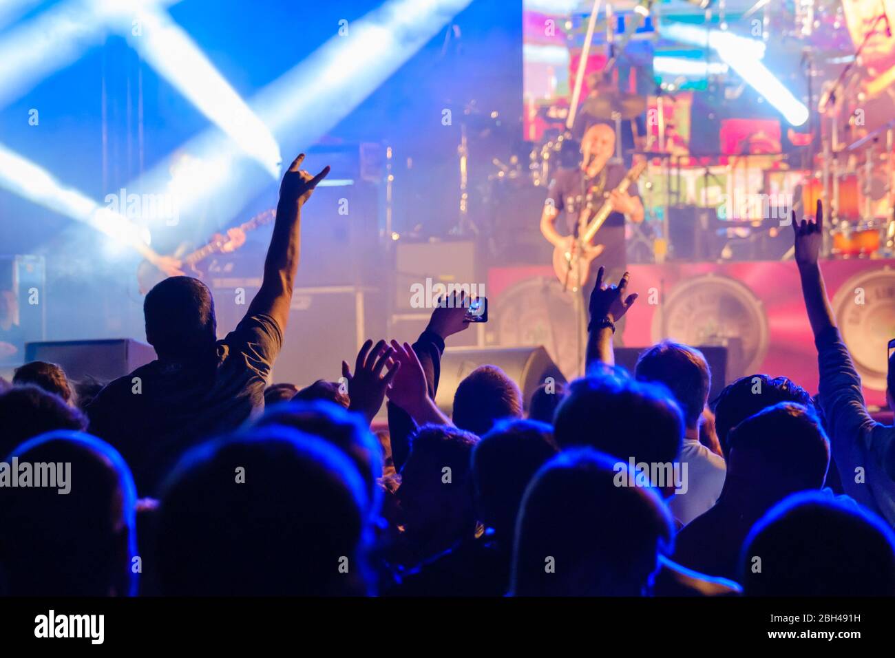 Silhouettes of people enjoying live concert of musician band performing  song on stage in bright spotlights Stock Photo - Alamy