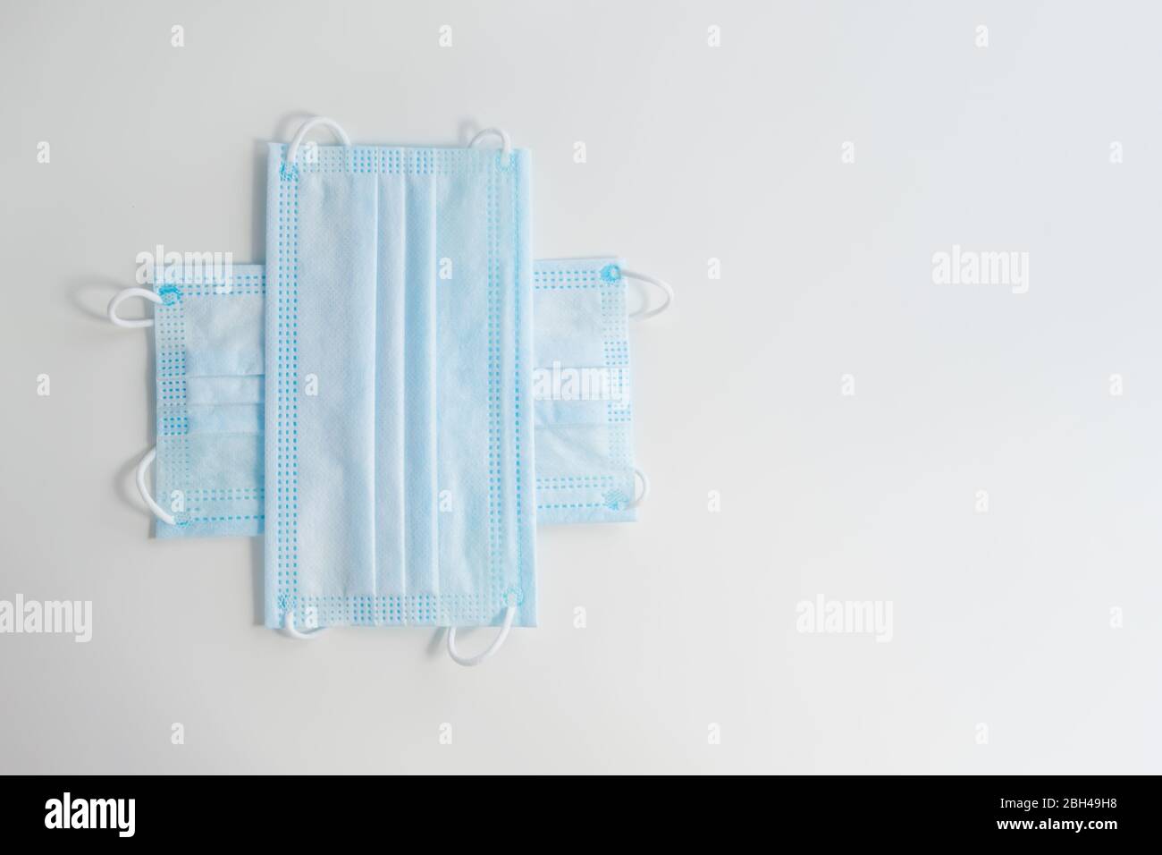 The cross of blue medical protective face masks with copy space for text. Protection measures against coronavirus concept. Stock Photo
