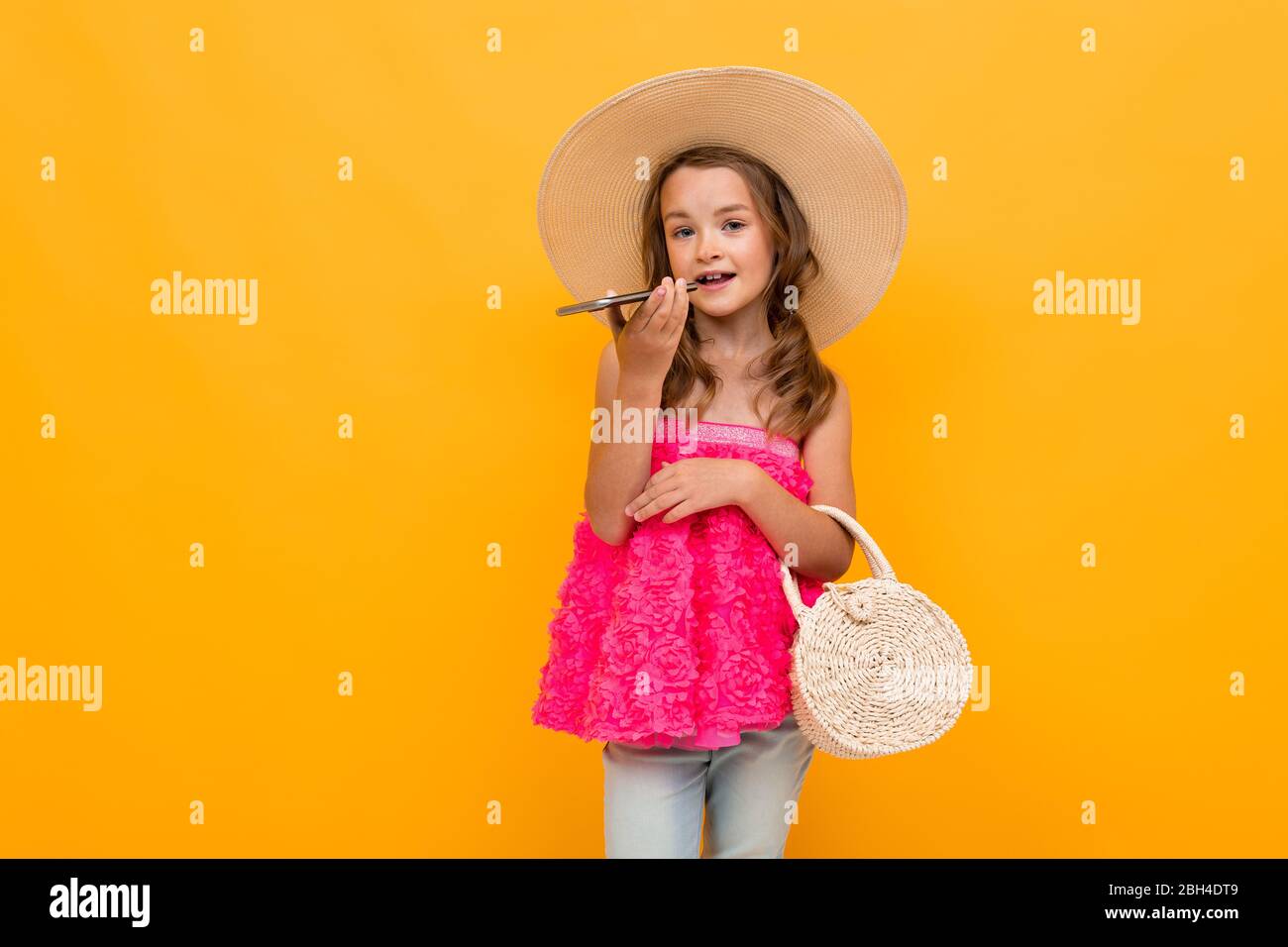 Caucasian fashionable girl in a straw hat with a round bag writes a ...