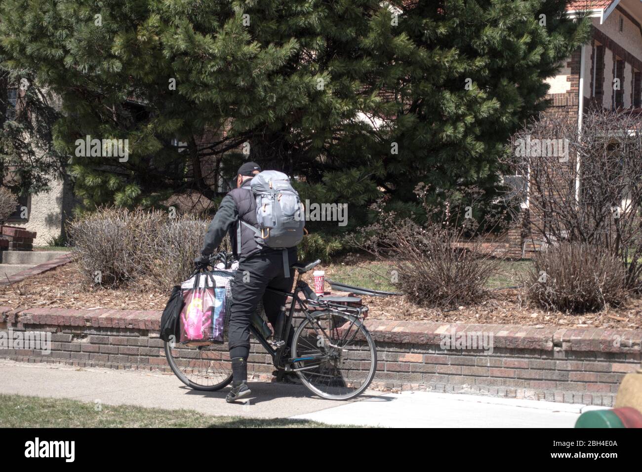 Man on bicycle loaded with packages. Could be homeless or delivering food and supplies during the Covid-19 pandemic. St Paul Minnesota MN USA Stock Photo