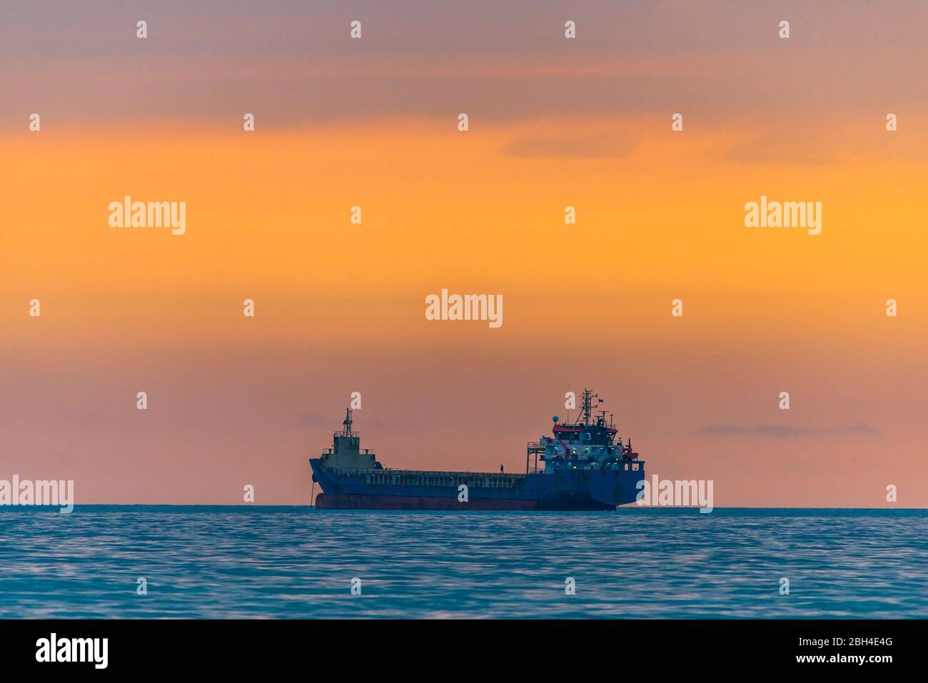 Cargo ship sailing the sea at a golden sunset or sunrise. Ocean ...