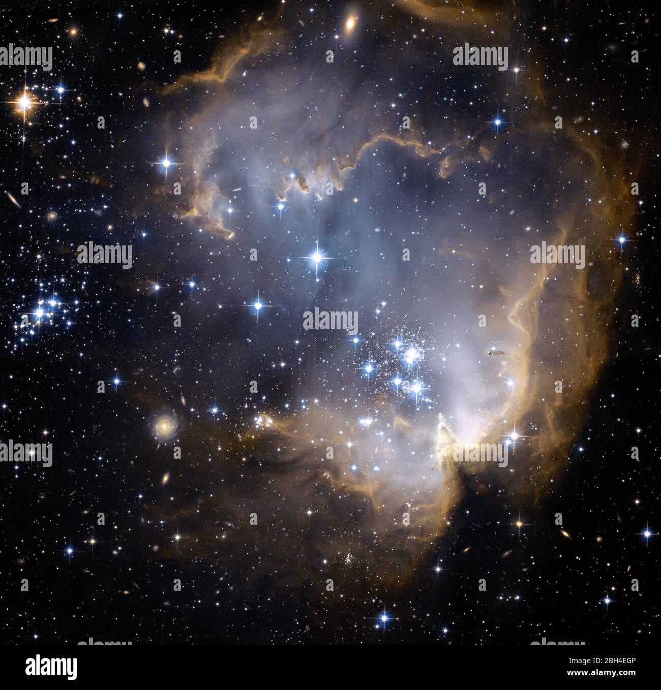 This image depicts bright blue newly formed stars that are blowing a cavity in the center of a fascinating star-forming region known as N90. The high energy radiation blazing out from the hot young stars in N90 is eroding the outer portions of the nebula from the inside, as the diffuse outer reaches of the nebula prevent the energetic outflows from streaming away from the cluster directly.  Stock Photo