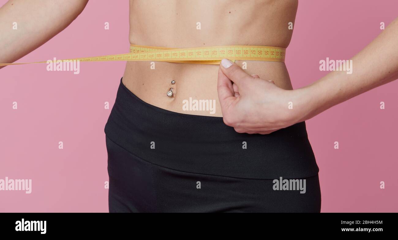 Fitness, workout, healthy lifestyle and diet concept - thin athletes women measure waist after exercise. Quarantine online training Stock Photo
