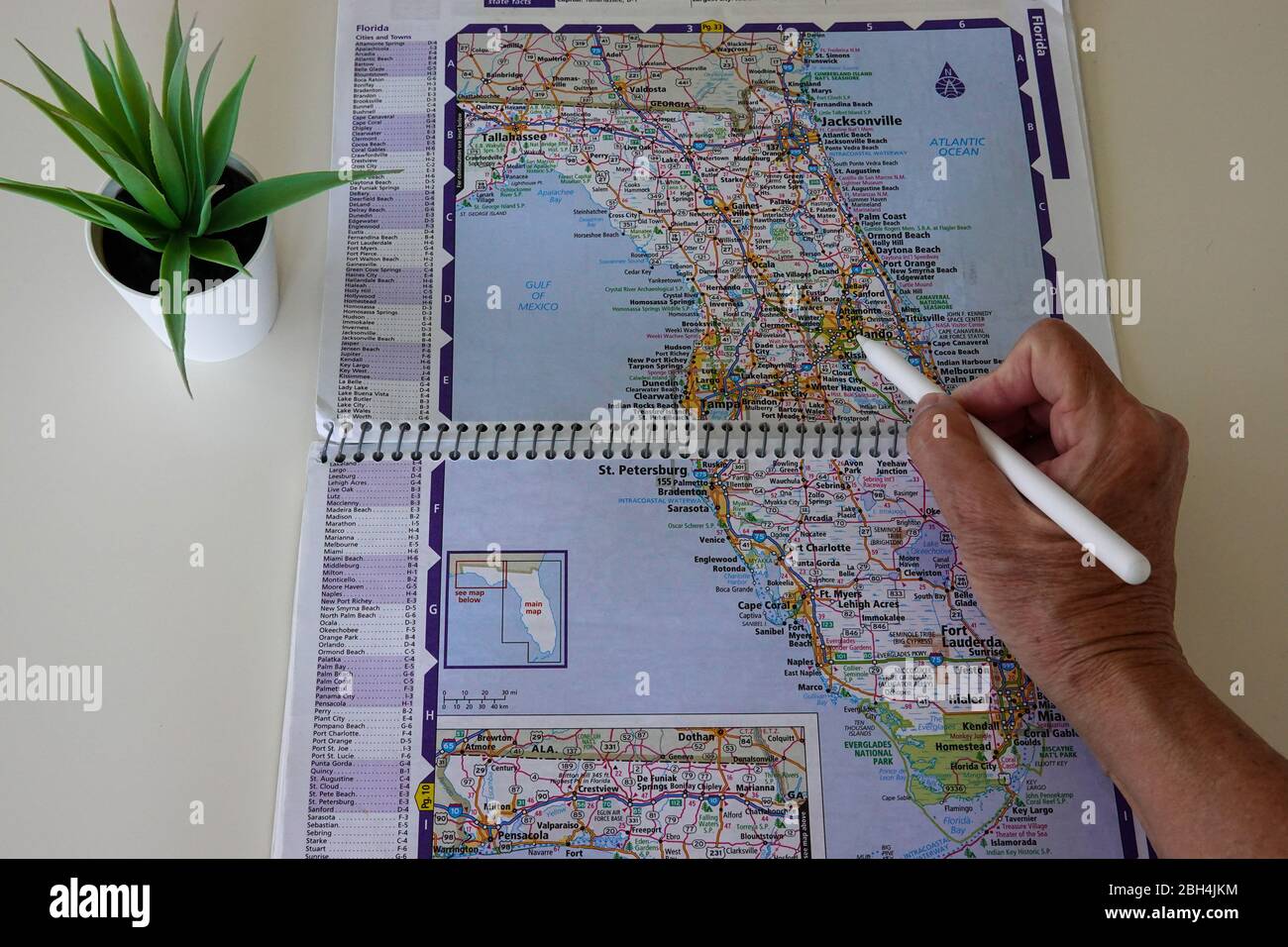 A person with a pen pointing at a paper map of Orlando, Florida in the