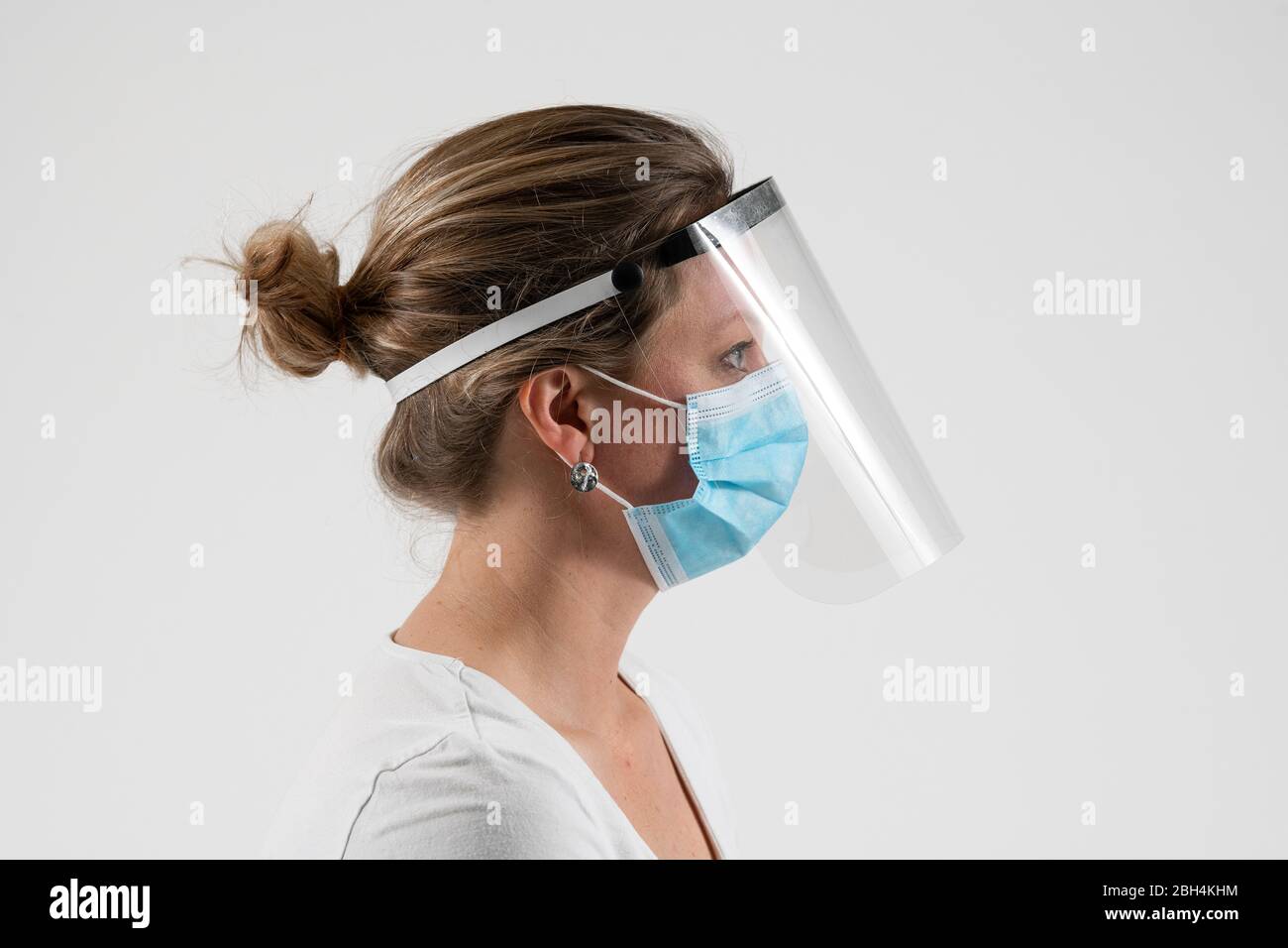 A woman wears a face shield manufactured by a volunteer initiative set up to supply PPE during the Coronavirus pandemic in the United kingdom. Stock Photo