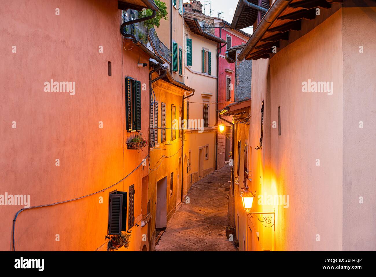 Chiusi, Italy empty street narrow alley in small historic town village in Tuscany during summer evening night with nobody, orange yellow lamp illumina Stock Photo