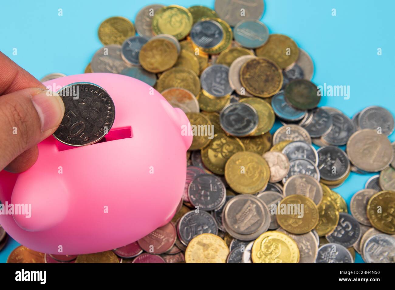 Casual man putting some coins into a piggy bank in living room Stock ...
