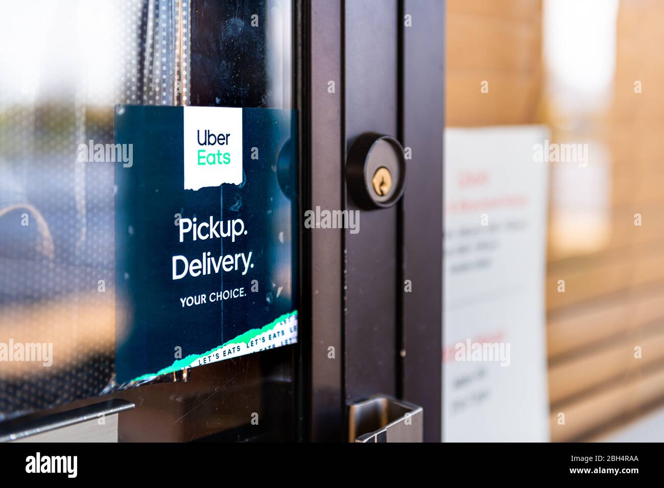 Herndon, USA - April 9, 2020: Virginia Fairfax County with sign and door entrance for restaurant and take out during coronavirus using Uber Eats Stock Photo