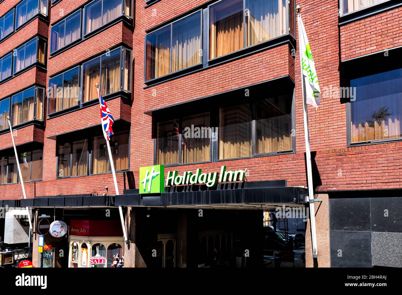 London, UK - June 22, 2018: Berkeley street in downtown Mayfair with sign for Holiday Inn hotel building and flags Stock Photo