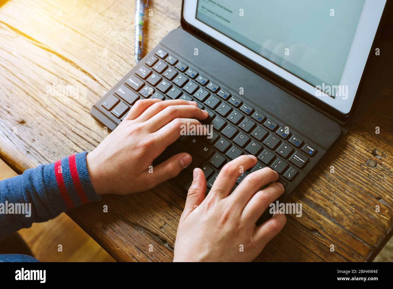 Young student types on a computer during home school while quarantined ...