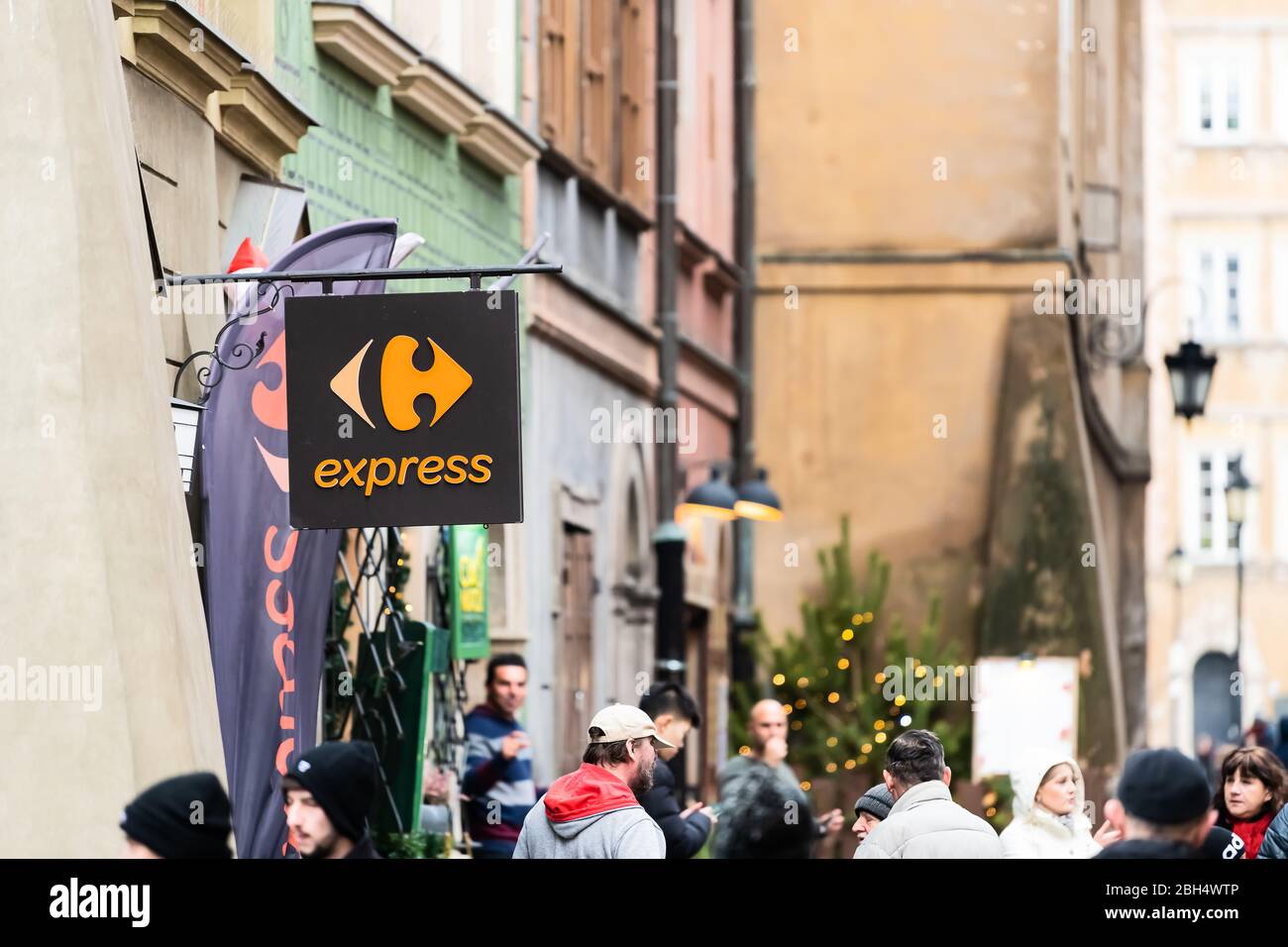 Warsaw, Poland - December 25, 2019: Carrefour express convenience grocery store shop sign in historic old town by market square with people walking by Stock Photo